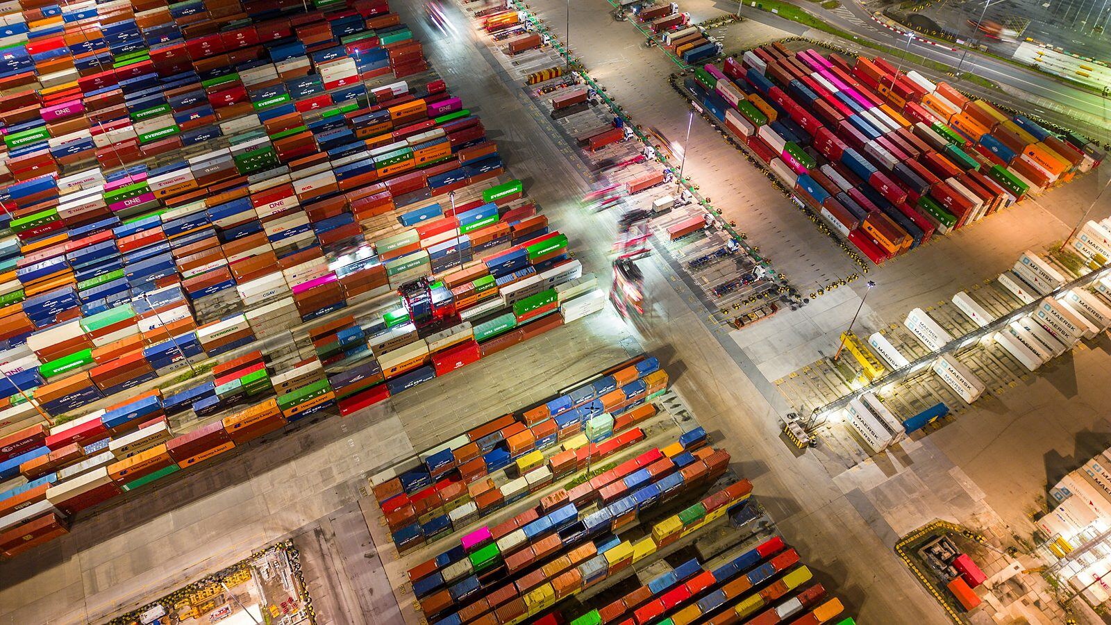 Aerial view of a container terminal working through the night, trucks moving between the stacks